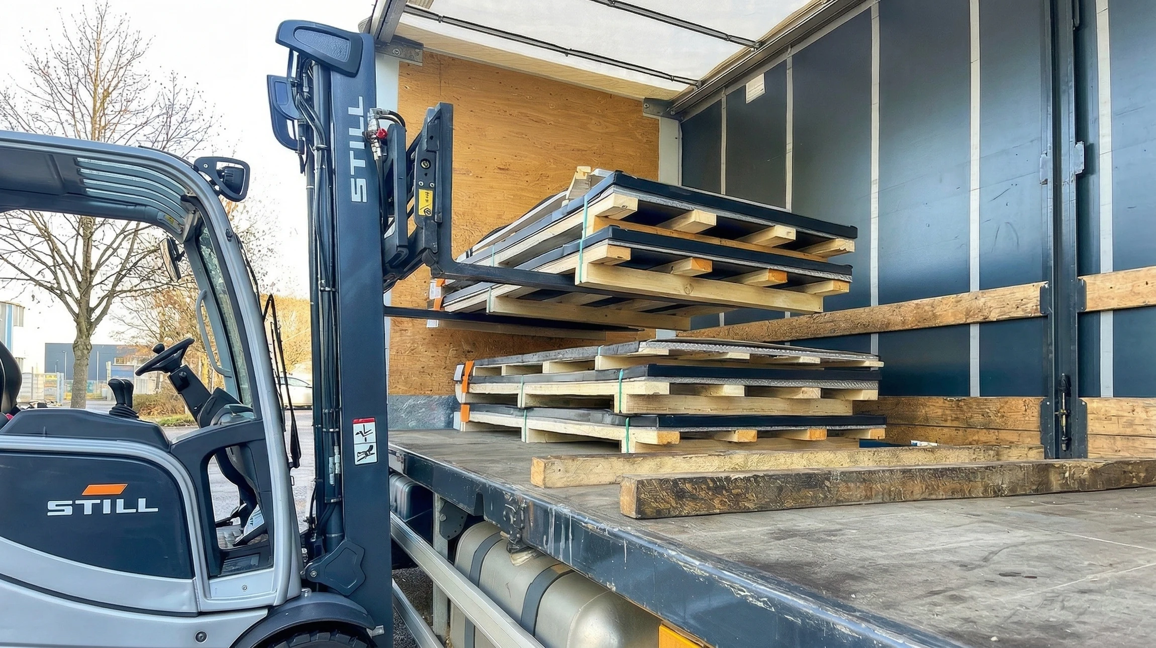 Le chariot élévateur à fourche dépose les marchandises de l'entrepôt au camion à l'extérieur sur fond ensoleillé